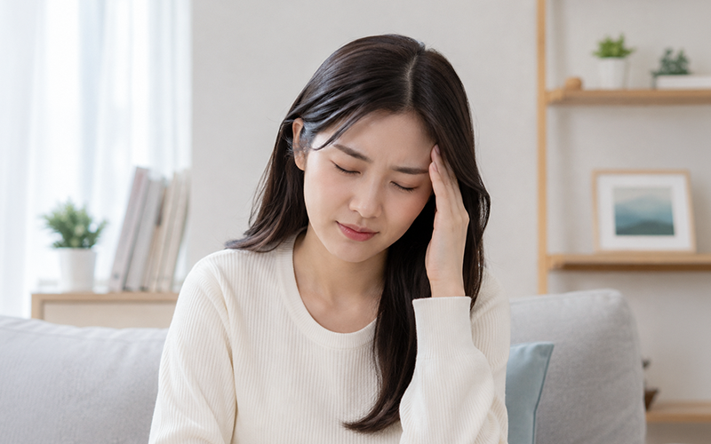 두통으로 관자놀이를 짚고 있는 여성