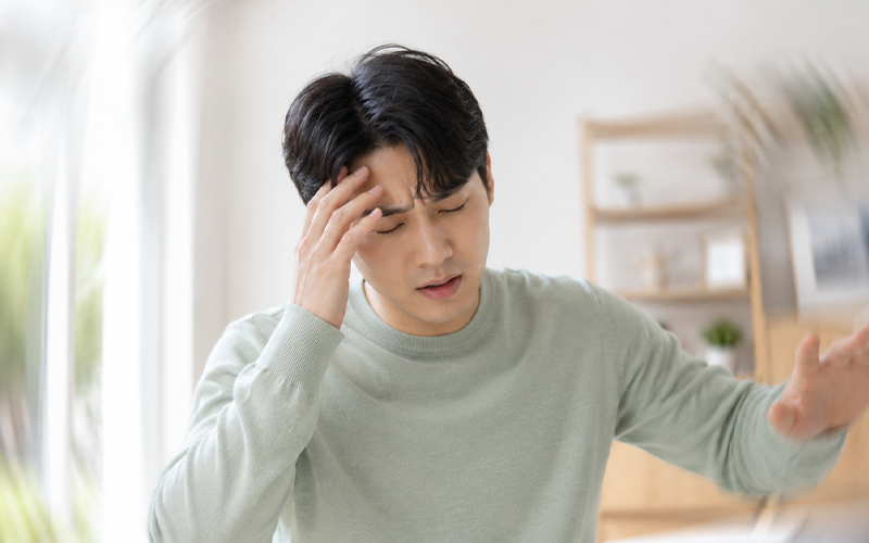 어지럼증으로 이마를 짚고 몸을 지탱하는 남성