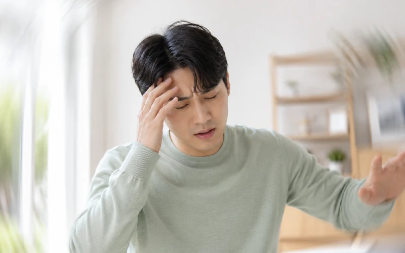 어지럼증으로 이마를 짚고 몸을 지탱하는 남성